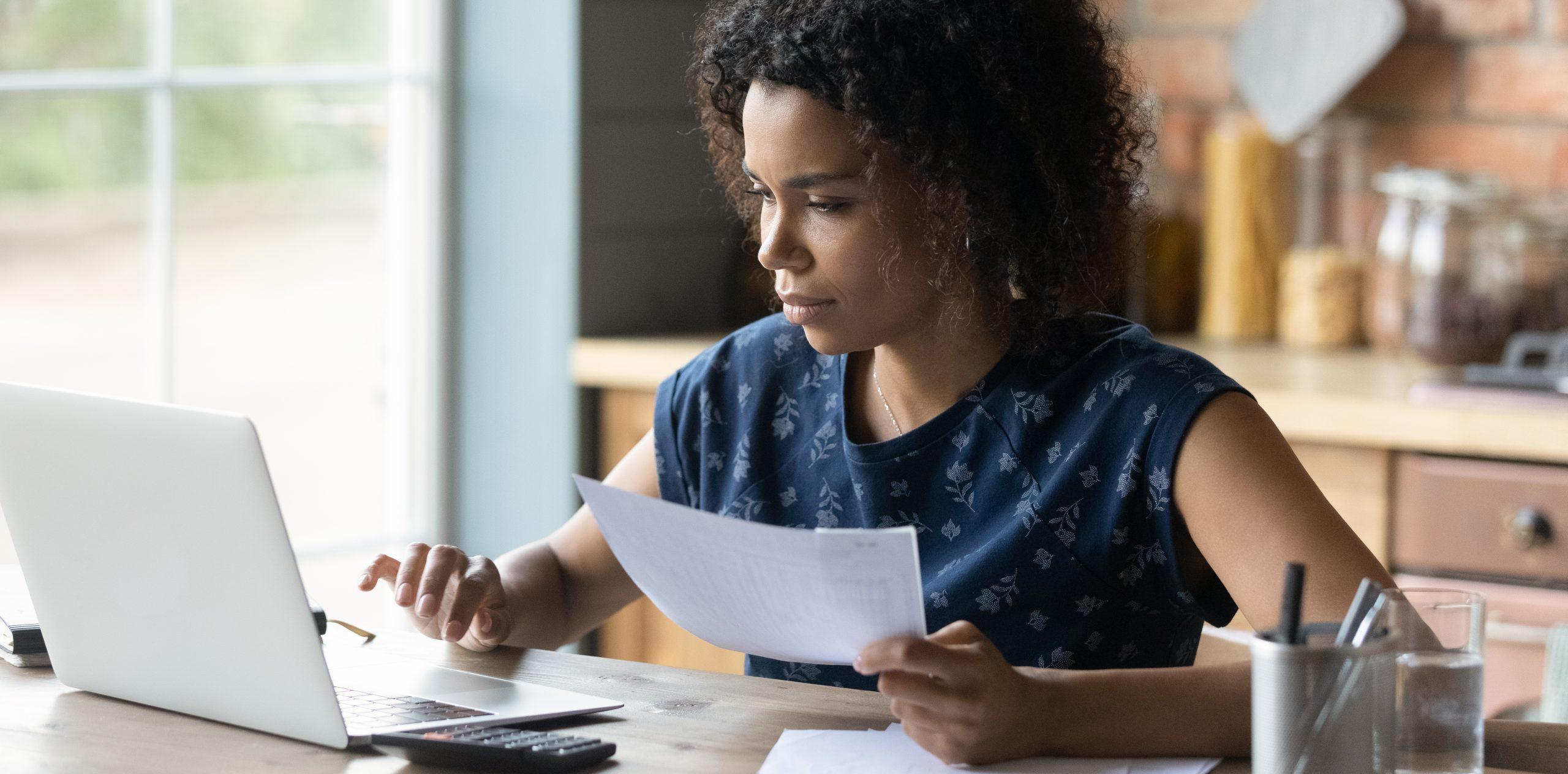 Serious millennial African American woman calculating taxes